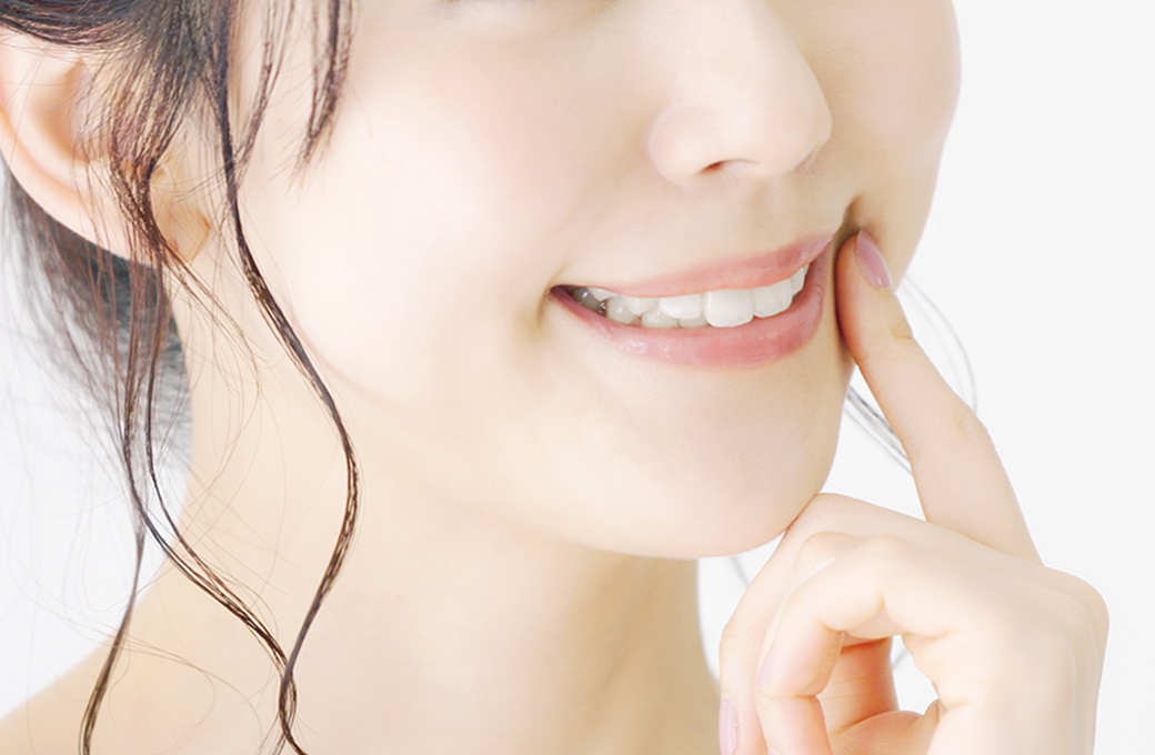 笑顔で口元を指さす女性